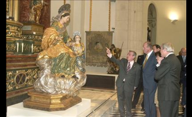 Su Majestad el Rey, acompañado por la ministra de Cultura y el presidente de la Región de Murcia, atienden a las explicaciones del comisario de la mue