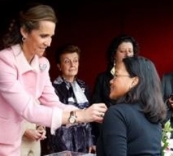 La Infanta Doña Elena coloca la insignia a una mujer en la mesa que presidió en el Día de la Banderita de Cruz Roja