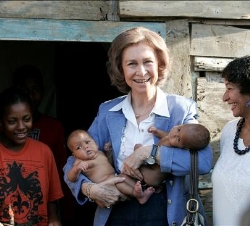 Su Majestad la Reina sostiene dos bebés durante la visita que realizó al barrio de Los Mina en Santo Domingo, a orillas del río Ozama