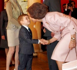 Los Reyes saludan a un niño durante la recepción a la colectividad española en Lituania