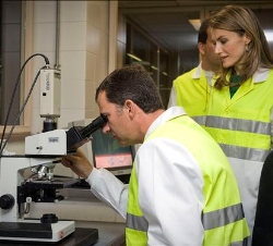 Don Felipe observa a través de un microscopio en presencia de Doña Letizia