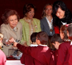 La Reina conversa con unos niños en la mesa de cuestación