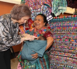 Doña Sofía, con una vendedora del mercado de artesanía y su bebé.