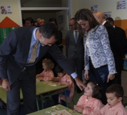 Don Felipe saluda cariñosamente a una niña, en presencia de Doña Letizia, durante su recorrido por las aulas de educación infantil