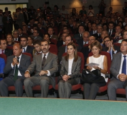 Sus Majestades los Reyes en el salón de actos del Recinto Ferial de Zafra acompañados por las autoridades presentes en el acto