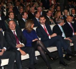 Su Majestad el Rey en la primera fila de asientos, conversa con la ministra de Empleo y Seguridad Social, Fátima Báñez