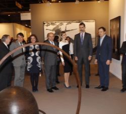 Sus Majestades los Reyes observan una de las obras expuestas en Arco, durante su visita