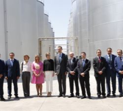 Sus Majestades los Reyes acompañados por las autoridades asistentes en la visita a las instalaciones de la Cooperativa Virgen de las Viñas