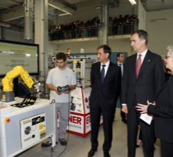 Sus Majestades los Reyes durante el recorrido por el taller de formación atienden las explicaciones a cargo de la directora de Recursos Humanos de Vol