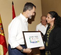 Su Majestad el Rey recibe de manos de la consejera ejecutiva de Relaciones Internacionales y Expansión Exterior de ONCE, miembro del Consejo de ONCE y