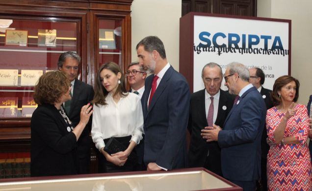 Sus Majestades los Reyes atienden a las explicaciones de la comisaria de la muestra, Margarita Becedas, durante su recorrido por la exposición