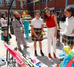 Su Majestad la Reina escucha las explicación por parte de dos alumnas de sus proyecto