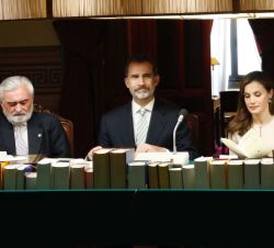 Sus Majestades los Reyes, en la Sala de Plenos, ocupan su lugar en la mesa junto al director de la Real Academia Española