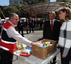 Doña Letizia recibe explicaciones de una de las personas voluntarias sobre el proceso de clasificación, elaboración y embalaje de despensas