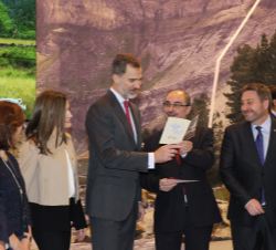 Sus Majestades los Reyes en el stand de Aragón, observan un folleto junto al presidente, Francisco Javier Lambán