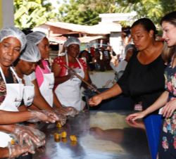 Su Majestad la Reina conversa con un grupo de mujeres que estaban preparando galletas con harina de excedentes de banano