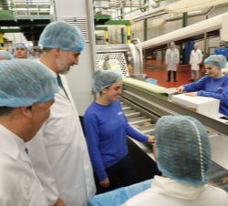 Su Majestad el Rey conversa con una trabajadora durante su visita a las instalaciones de Galletas Gullón