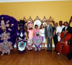 Sus Majestades los Reyes junto al grupo musical de la actuación y los trajes tradicionales del 'Mardi Gras'