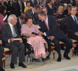 Su Majestad el Rey en primera fila de asientos conversa con Su Alteza Real la Infanta Doña Margarita