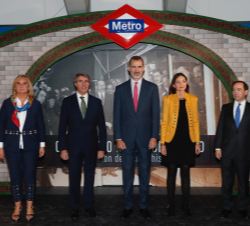Fotografía de grupo de Su Majestad el Rey con las autoridades y personalidades, ante una fotografía de la inauguración del Metro por el Rey Alfonso XI