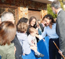 Sus Majestades saludan a un niño que asiste a su visita a Mual