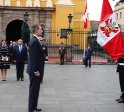 Su Majestad el Rey ante la bandera de la República del Perú durante la ceremonia de bienvenida