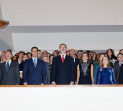 Sus Majestades los Reyes, acompañados de las autoridades asistentes al acto, durante la interpretación del Himno Nacional