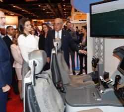 Sus Majestades los Reyes observan un simulador de vuelo en el expositor de Air Europa