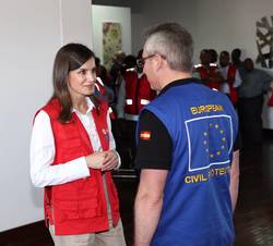 Su Majestad la Reina conversa con uno de los responsables de la coordinación de la operación de asistencia internacional humanitaria