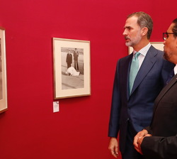 Su Majestad el Rey ante una fotografía de Su Majestad el Rey Don Juan Carlos junto a Sus Altezas Reales la Infanta Elena y la Infanta Cristina, así co