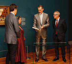 Su Majestad el Rey observa un catalogo de la exposición