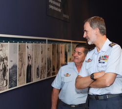 Su Majestad el Rey observa unas fotografías durante el recorrido de su visita