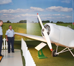 Su Majestad ante un avión biplaza durante la visita
