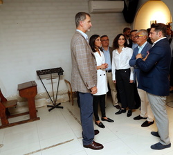 Sus Majestades los Reyes conversan con el propietario del estudio de fotografía los daños ocasionados por la inundación