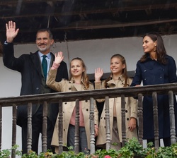 Sus Majestades los Reyes, Su Alteza Real la Princesa de Asturias y Su Alteza Real la Infanta Doña Sofía saludan desde la balconada de una casa típica 