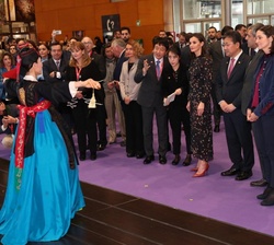 Su Majestad la Reina observa una pieza de folclore coreano durante su paso por el stand de ese país asiático