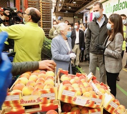 Don Felipe y Doña Letizia conversan con una empleada de un puesto de las naves de frutas y verduras