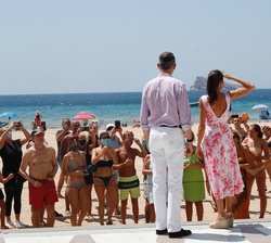 Sus Majestades los Reyes conversan con varios turistas durante el recorrido realizado por el paseo marítimo de la Playa de Levante