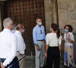 La directora del Museo Diocesano, Belén Luque, explica a Sus Majestades los Reyes la tradición de la colocación de una bandera blanca sobre el punto m