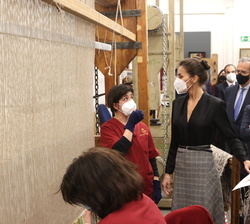 Sus Majestades los Reyes observan la fabricación de una alfombra