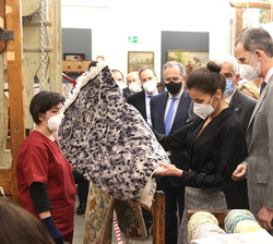 Sus Majestades los Reyes observan la fabricación de una alfombra