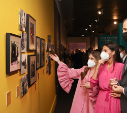 La comisaria de la exposición da explicación de las fotografías expuestas a Sus Majestades los Reyes