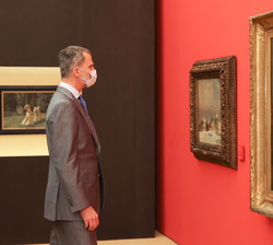 Su Majestad el Rey observa uno de los cuadros de la exposición