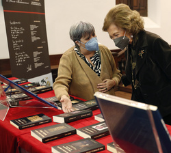 Doña Sofía junto a la galardonada observan unos ejemplares de las ediciones anteriores del Premio
