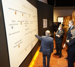 Don Felipe atiende a la explicación del comisario de la exposición del panel "Origen Familiar"