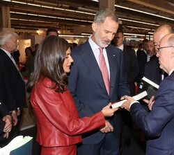 Sus Majestades los Reyes observan un libro durante su recorrido por la Feria del Libro de Fráncfort