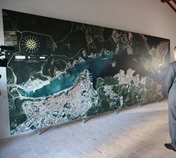 Sus Majestades los Reyes contemplan una fotografía aérea de la Isla del Rey