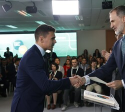 Su Majestad el Rey hace entrega del título a uno de los becados