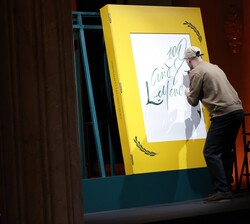 Momento en el que un calígrafo, caligrafía la portada del Gran Libro