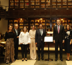 Fotografía de grupo de Sus Majestades los Reyes ante una placa conmemorativa con las autoridades y personalidades asistentes al acto